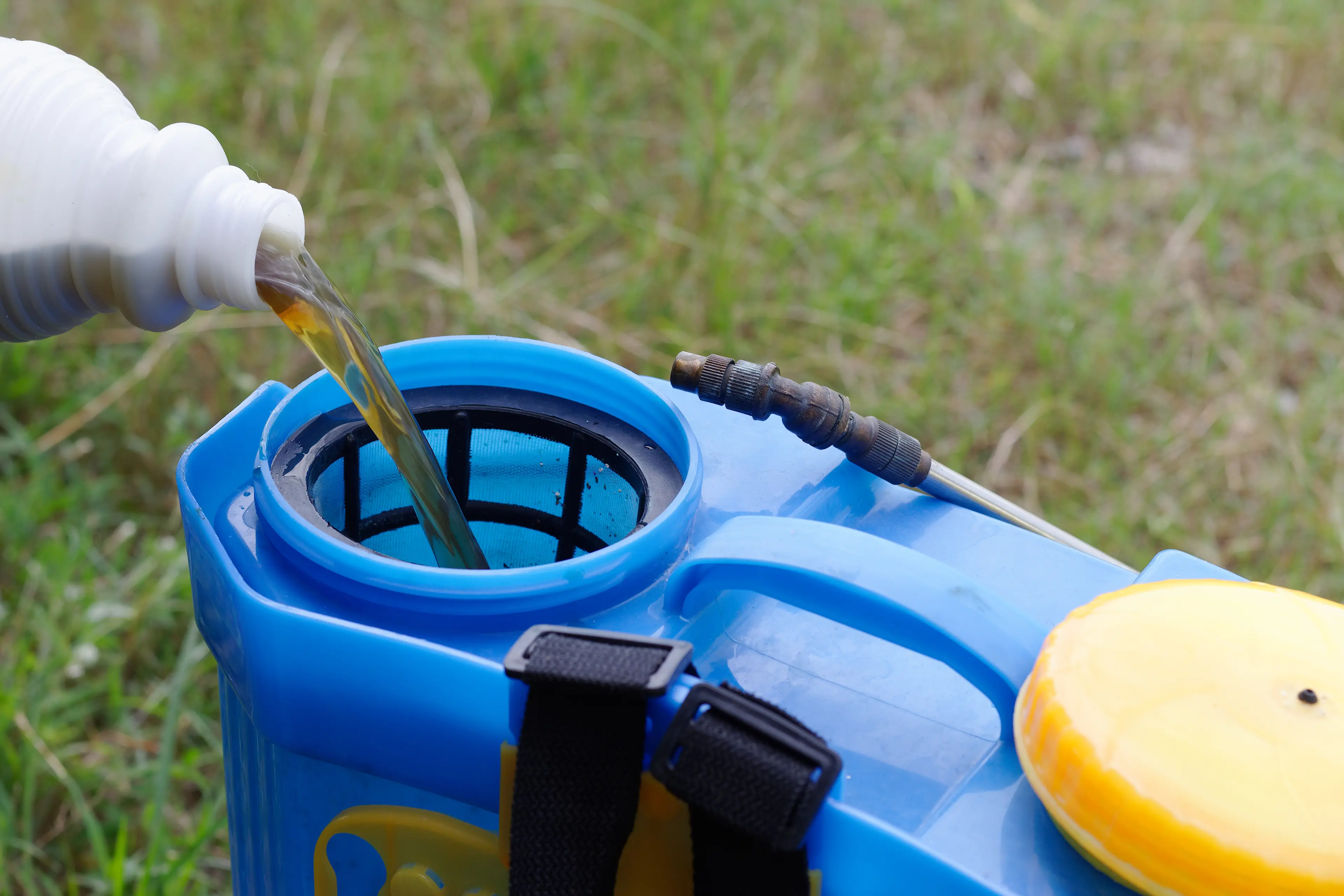 <p>pouring herbicide water from bottle into tank sprayer</p>\\n