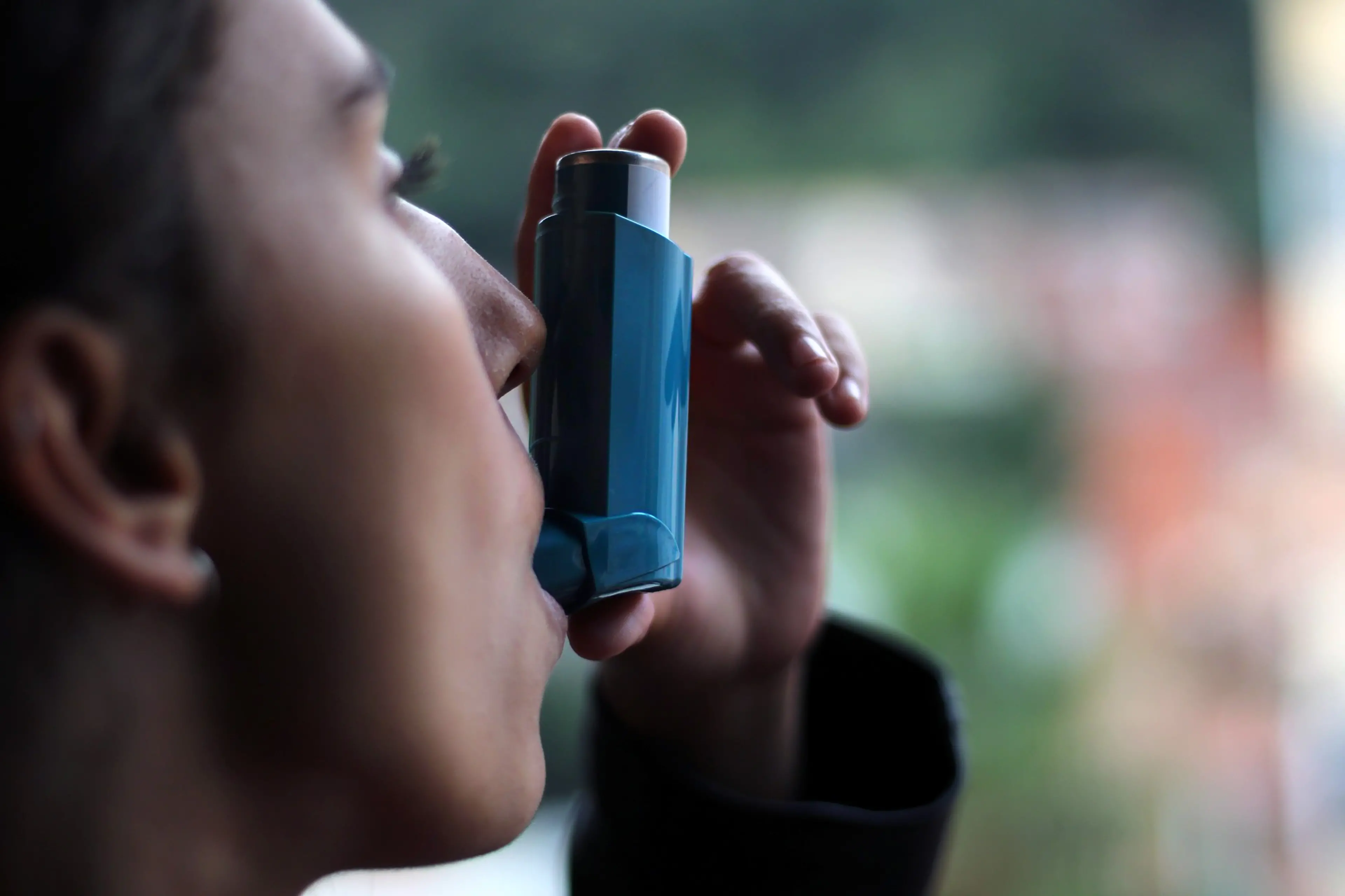 <p>Health and medicine - Young girl using blue asthma inhaler to prevent an asthma attack. Pharmaceutical product to prevent and treat asthma.</p>\\n